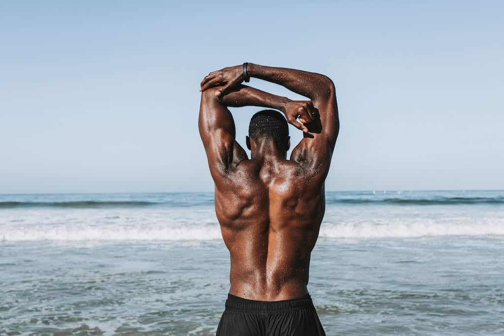 Photo of an athlete's back as he stands on a beach