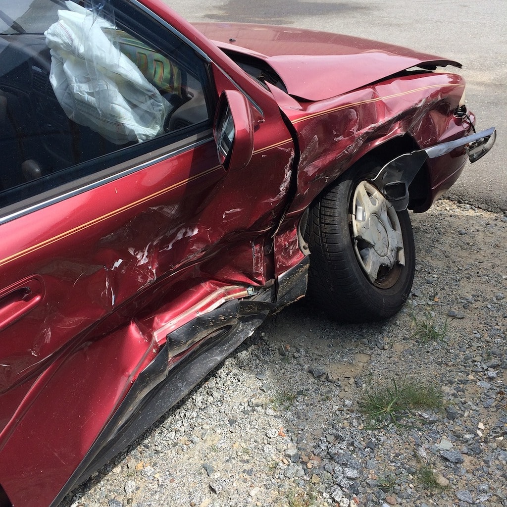 Photo of a red car with significant damage on its passenger door