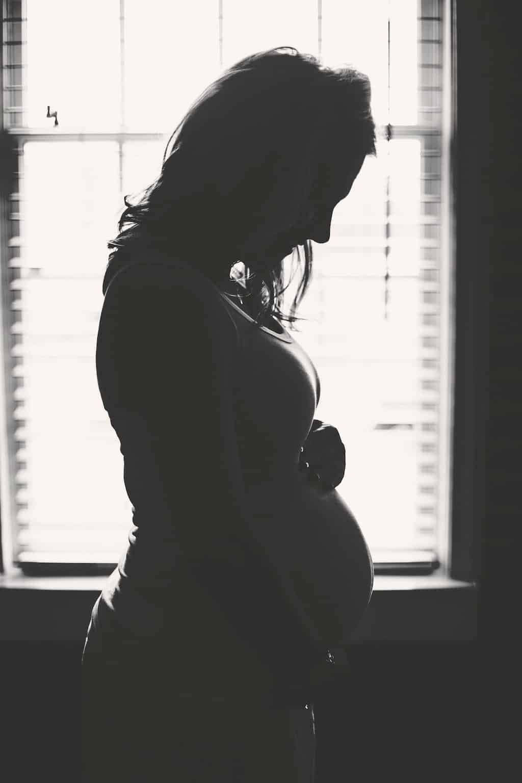 Black and white photo of a woman holding her pregnant belly
