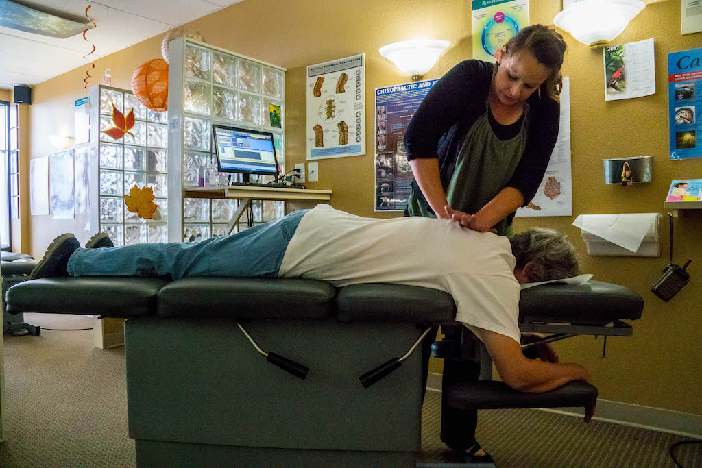 A female chiropractor treating a patient on a chiropractic treatment table