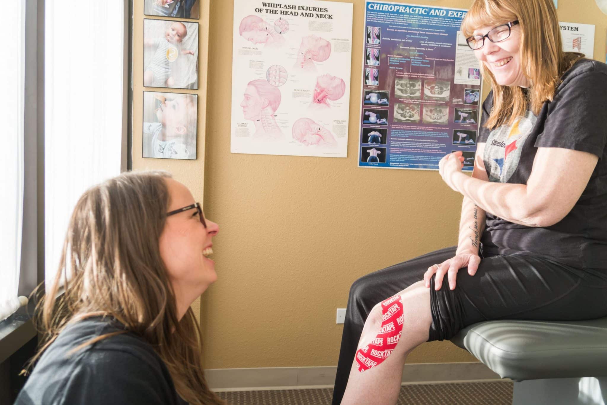A patient smiling at their doctor with medical tape on her knee