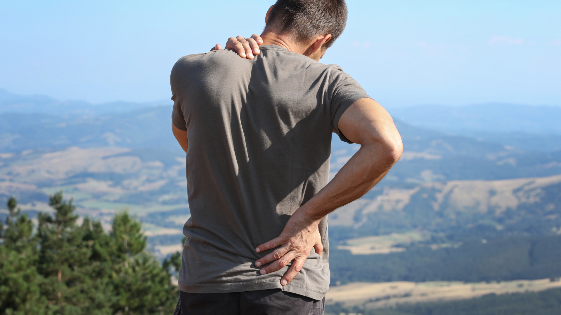 man feeling lower back pain while hiking